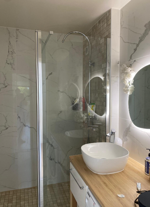 Douche vitrée et vasque dans une salle de bains effet marbre